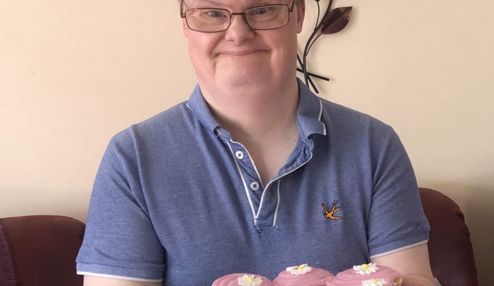 Harry Priestley House resident presents cupcakes during Learning Disability Week