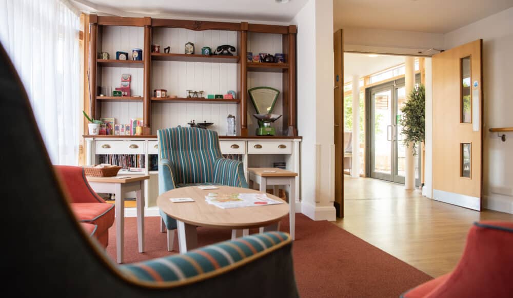 Communal seating area at James Terry Court, with comfortable seating, table and decorative shelves with ornaments and books