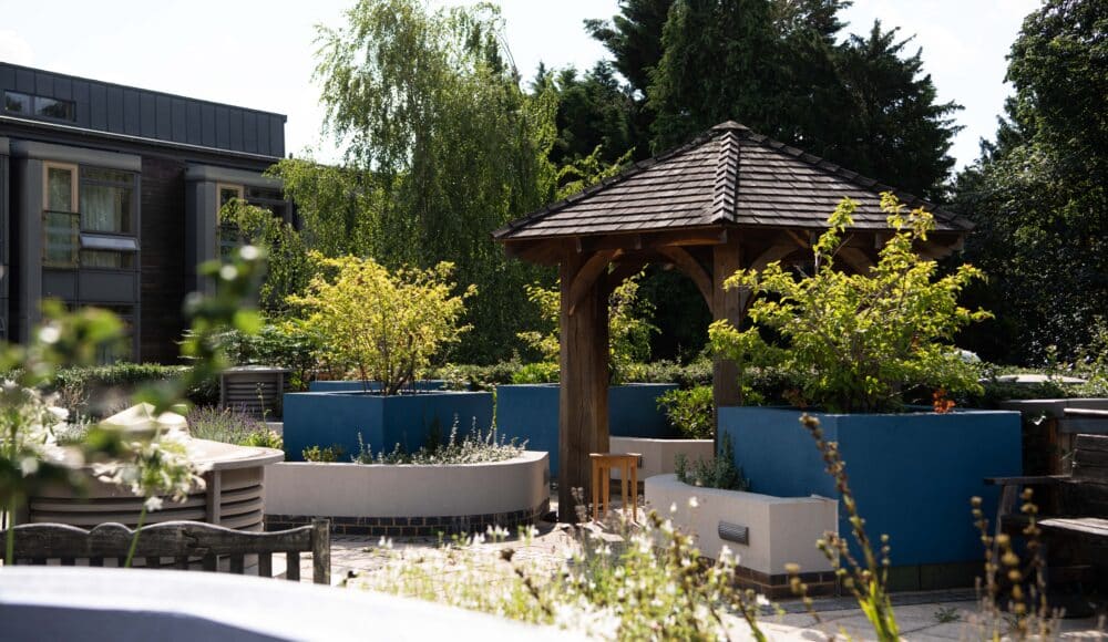 Pergola with benches, trees and greenery at the roof top gardens at James Terry Court care home.