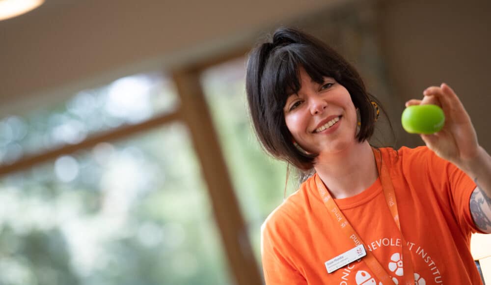 Activities Coordinator Suzie smiles while gently squeezing a green stress ball during an activity at James Terry Court care home