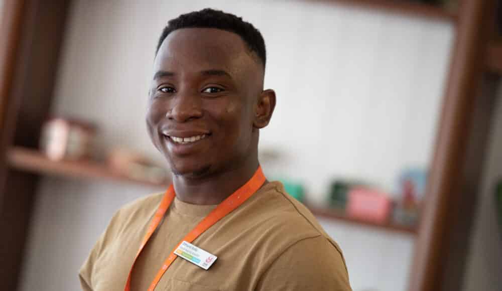 Staff member wearing a brown t-shirt smiling in the communal areas at James Terry Court care home
