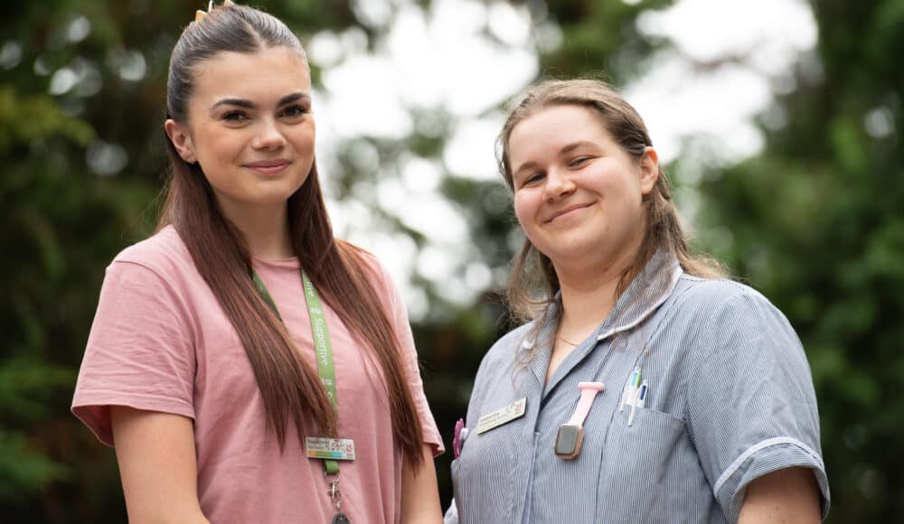 Two staff members pose outside in the gardens at James Terry Court care home.
