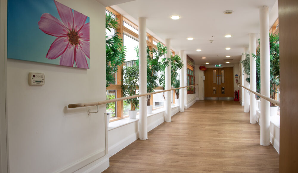 A hallway displaying a painting, connected to a calm garden with a gazebo and benches for enjoying the natural surroundings.