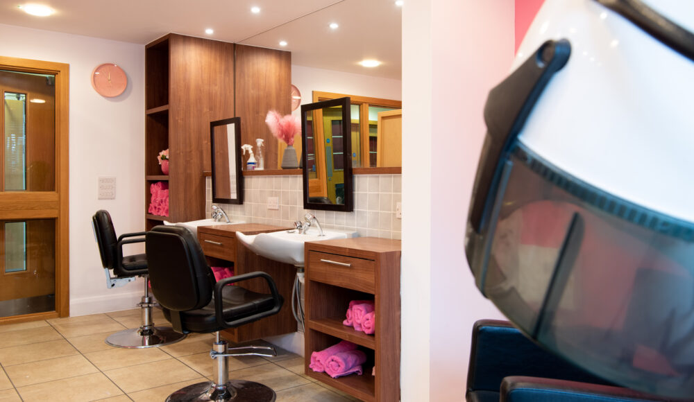 A bright salon featuring a large mirror above a sleek sink, creating a welcoming space for beauty treatments.