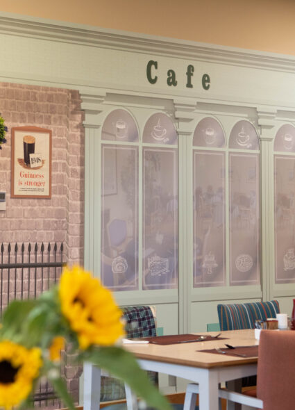 A cozy restaurant featuring a vibrant mural of a charming café on the wall, adding a warm ambiance to the space.