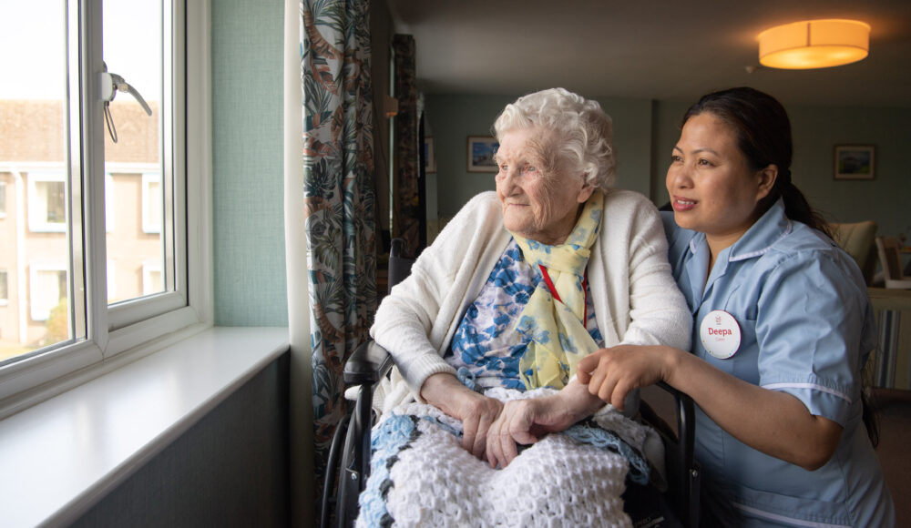 A caring nurse assists a resident in a wheelchair, showcasing compassion and support in a healthcare setting.