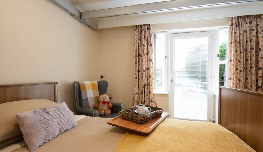 A cozy bed with a wooden tray on top, holding breakfast items and a small vase of flowers.