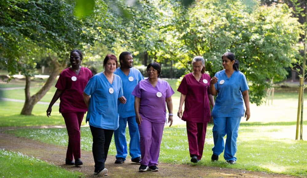 A group of nurses from Shannon Court care home, in Surrey strolls together in a sunny park, enjoying their break and the fresh air.