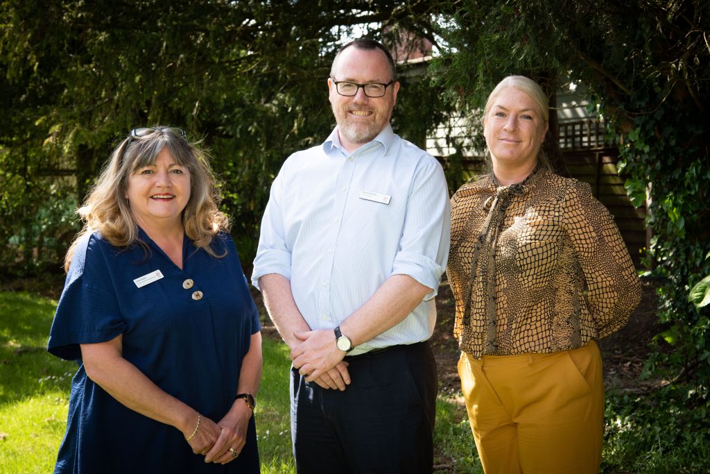 The Home Management Team stand together, radiating happiness in a beautiful outdoor scene.