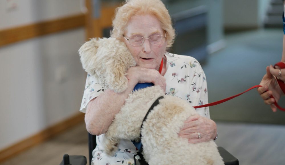 Resident durning an activities session gets to pat a young dog