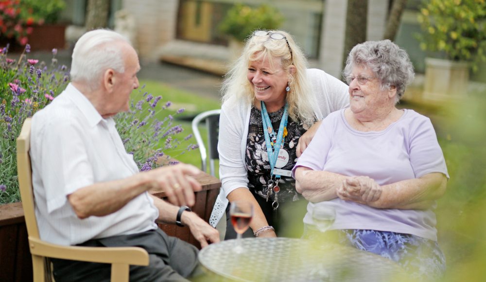 Staff member and residents in the garden at Albert Edward Prince of Wales Court