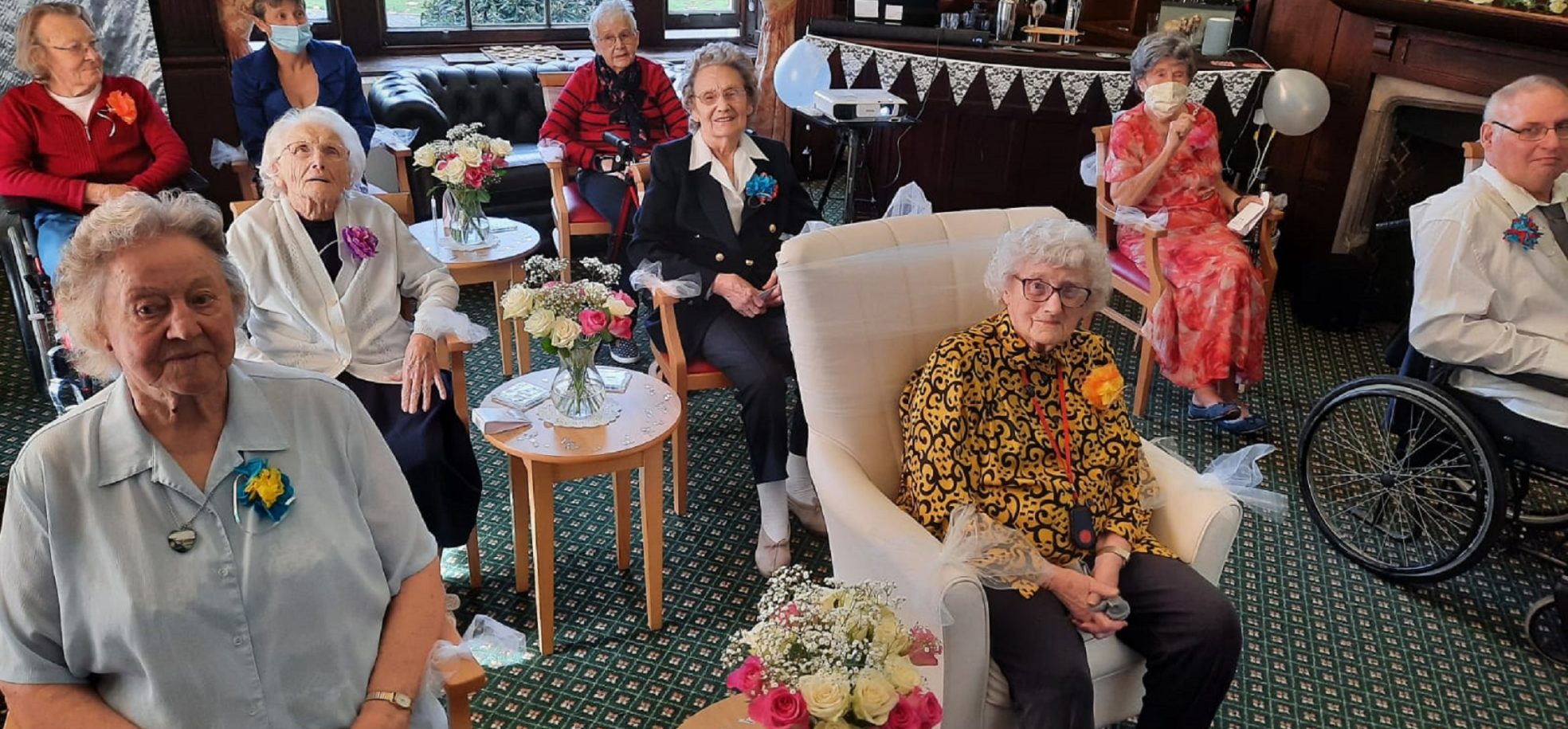 Prince Edward Duke of Kent Court resident Dot Bash (wearing a yellow patterned blouse) watching a live stream of her granddaughter’s wedding with fellow residents.