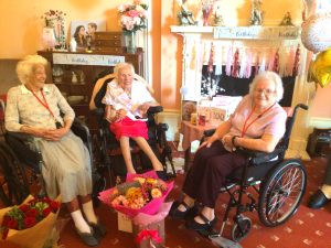 Residents Joycelyn Mills (left) and Kathleen Powis (right), who are 101 and 100 years old, respectively, congratulates Nina Ansell on her 100th birthday. Together, the three ladies have a combined age of 301.
