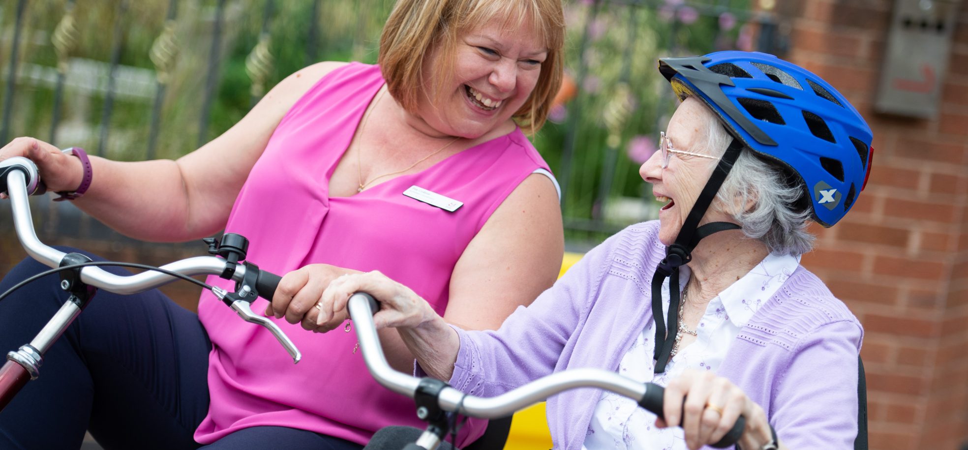 Staff member and resident riding a bike together at Devonshire Court, Leicester.