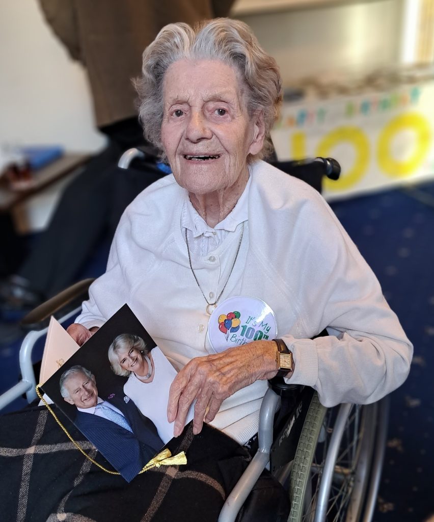 Prince Philip Duke of Edinburgh Court’s resident Joan Parr posing with her birthday card from the King and Queen Consort.  