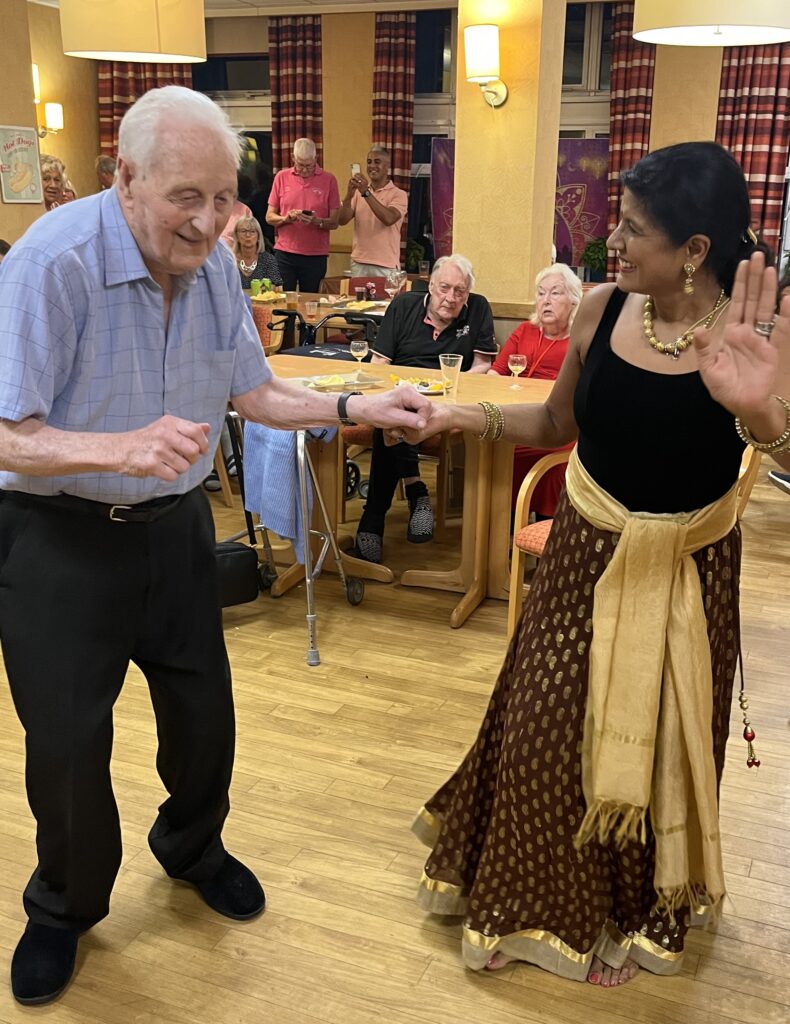 Resident Len Willis at RMBI Care Co. Home Prince George Duke of Kent Court, in Chislehurst, learning some dance moves from Jaya Parikh