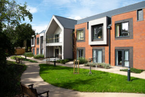 Exterior view of the Home, with a modern brickwork and a small landscaped area at the forefront, which includes newly planted trees.