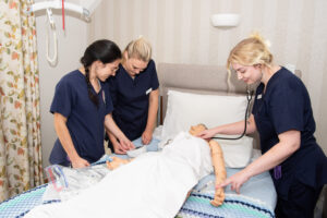 Three nurses carrying out training on a dummy. 