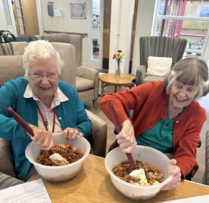 Residents Rita and Pam stir up the ingredients of their Christmas puddings at RMBI Care Co. Home Shannon Court, in Surrey. 