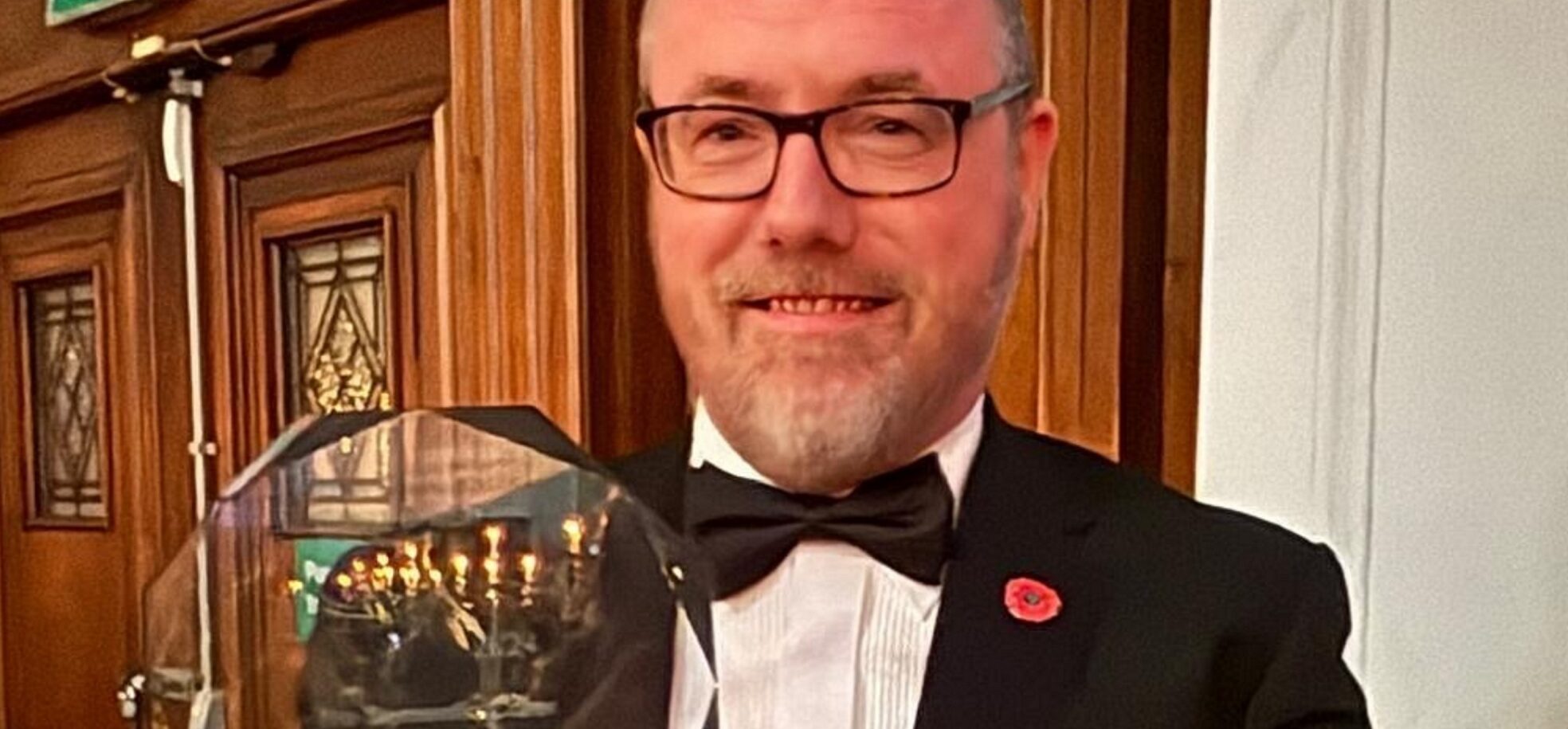 RMBI Care Co. Home The Tithebarn’s Care Home Manager, Simon Doherty in a black tuxedo, white shirt and glasses, holding his glass trophy at the Great British Care Awards ceremony for the North West region, in Manchester