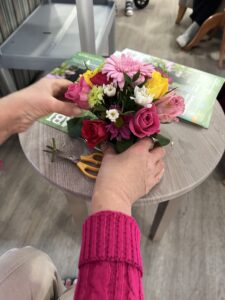 A person is engaged in cutting a beautiful flower arrangement on a table, demonstrating attention to detail in floral design.