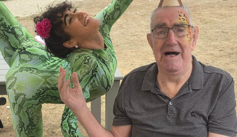 Prince Edward Duke of Kent Court resident Bill, wearing colourful makeup and a monkey paper hat, poses with guest contortionist Claudia.