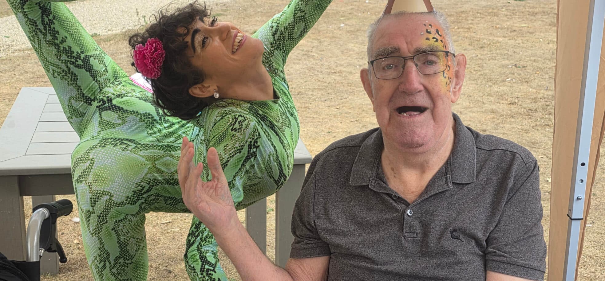 Prince Edward Duke of Kent Court resident Bill, wearing colourful makeup and a monkey paper hat, poses with guest contortionist Claudia.