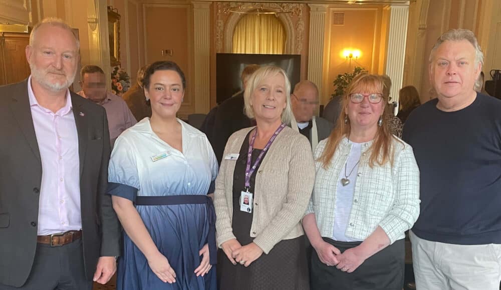 Two men and three women standing in a room in the care home.