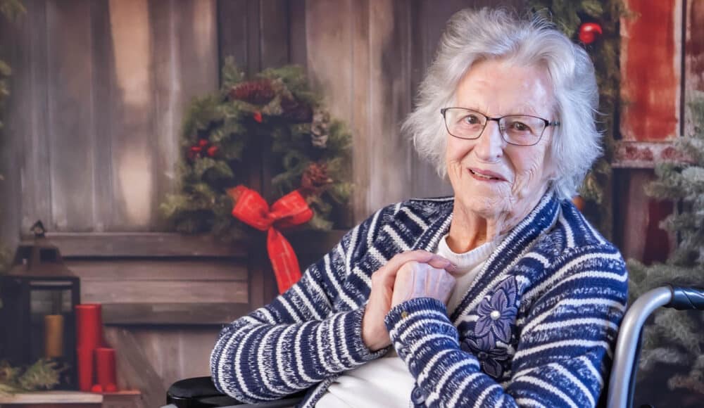 A care home resident smiles at the camera. There are Christmas ornaments behind her.