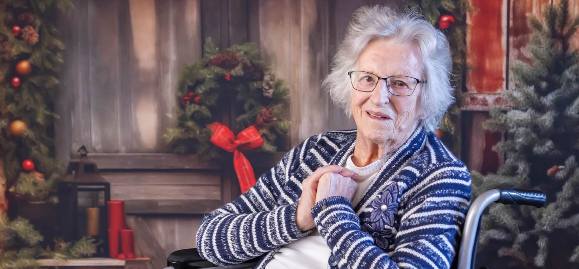 A care home resident smiles at the camera. There are Christmas ornaments behind her.