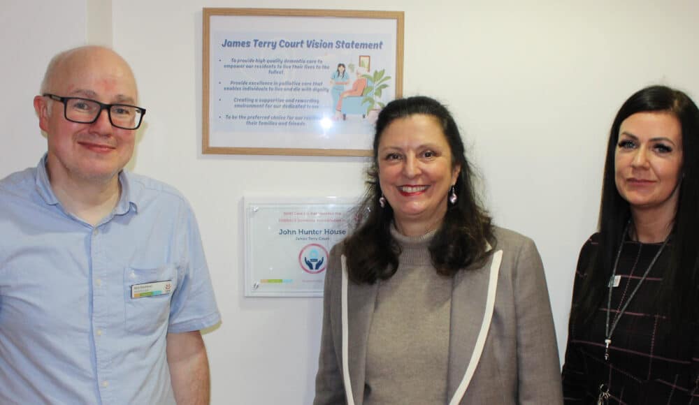Dementia lead, councillor and care home manager standing next to the dementia accreditation plaque.
