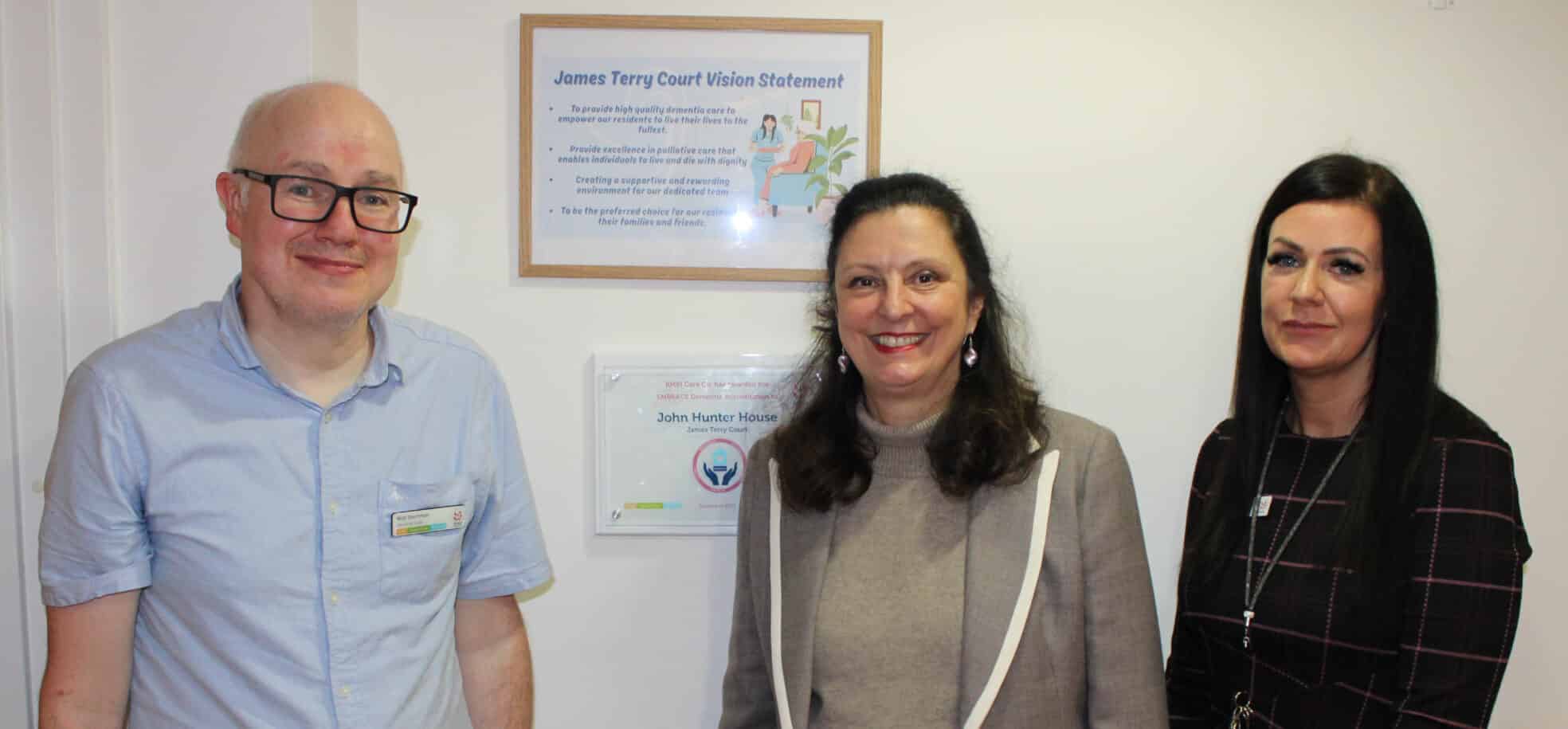 Dementia lead, councillor and care home manager standing next to the dementia accreditation plaque.