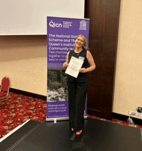 A care home nurse holds up a diploma at the awards event.