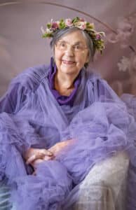 A care home resident smiling and wearing a crown.