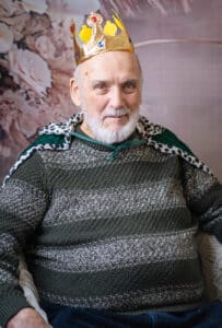 A care home resident wearing a cape and a crown.
