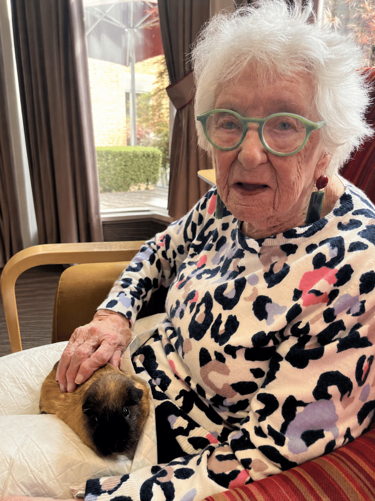 Resident Ivy enjoys holding a guinea pig at RMBI Care Co. Home Prince George Duke of Kent Court, in Chislehurst