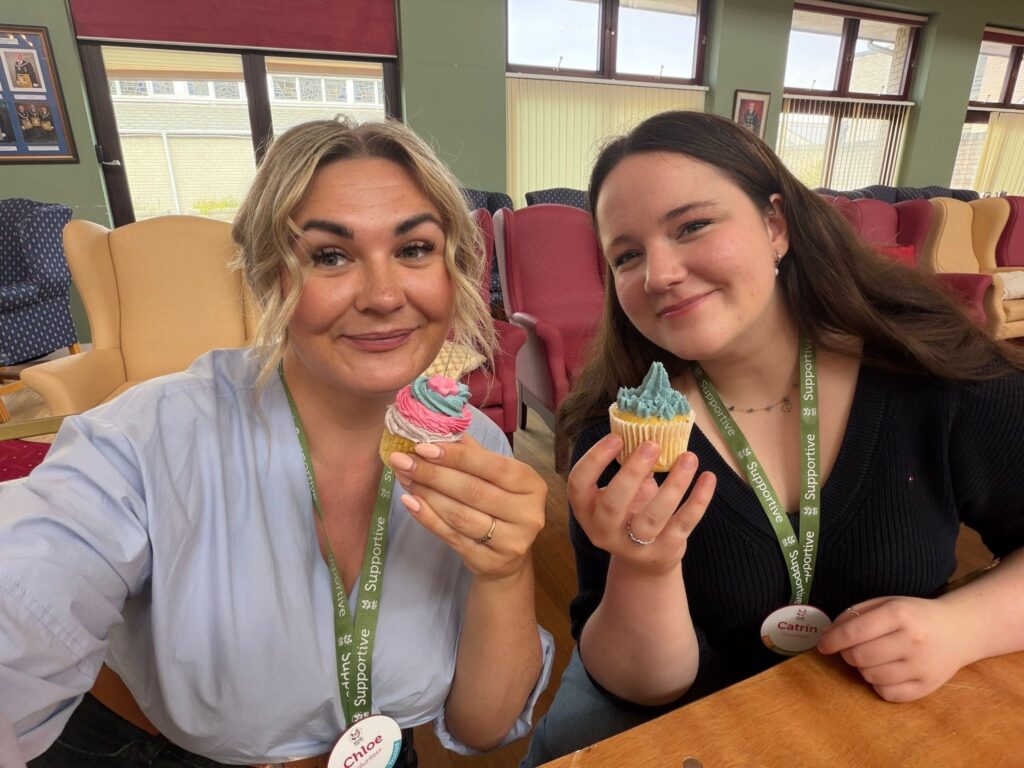 Two staff members Chloe and Catrin are delighted with their newly decorated cupcakes at RMBI Home Albert Edward Prince of Wales Court, in Porthcawl