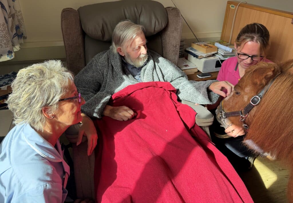 Minnie, the Shetland pony, nuzzles up to resident Stuart with staff member Si